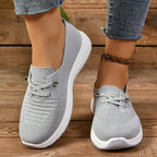 Women's light grey slip-on trainers with lace detail and white textured soles