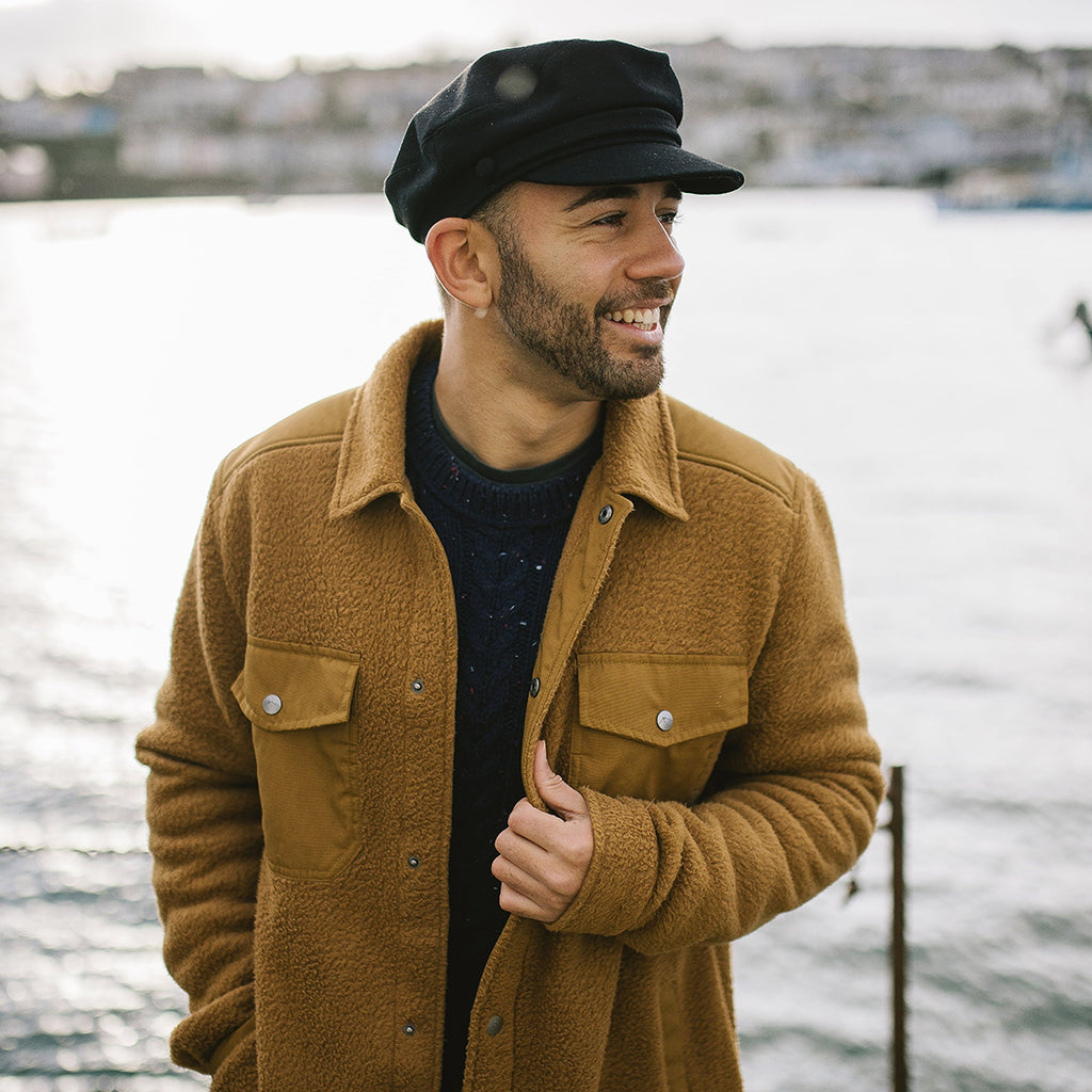 Black fiddler cap with structured crown, layered band and short brim