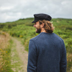 Black fiddler cap with structured crown, layered band and short brim