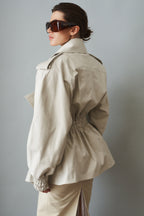 Women's cream trench coat with wide lapels, tie waist and elasticated cuffs