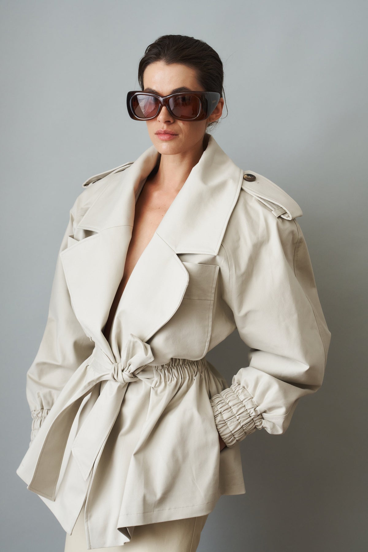 Women's cream trench coat with wide lapels, tie waist and elasticated cuffs
