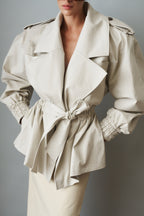 Women's cream trench coat with wide lapels, tie waist and elasticated cuffs