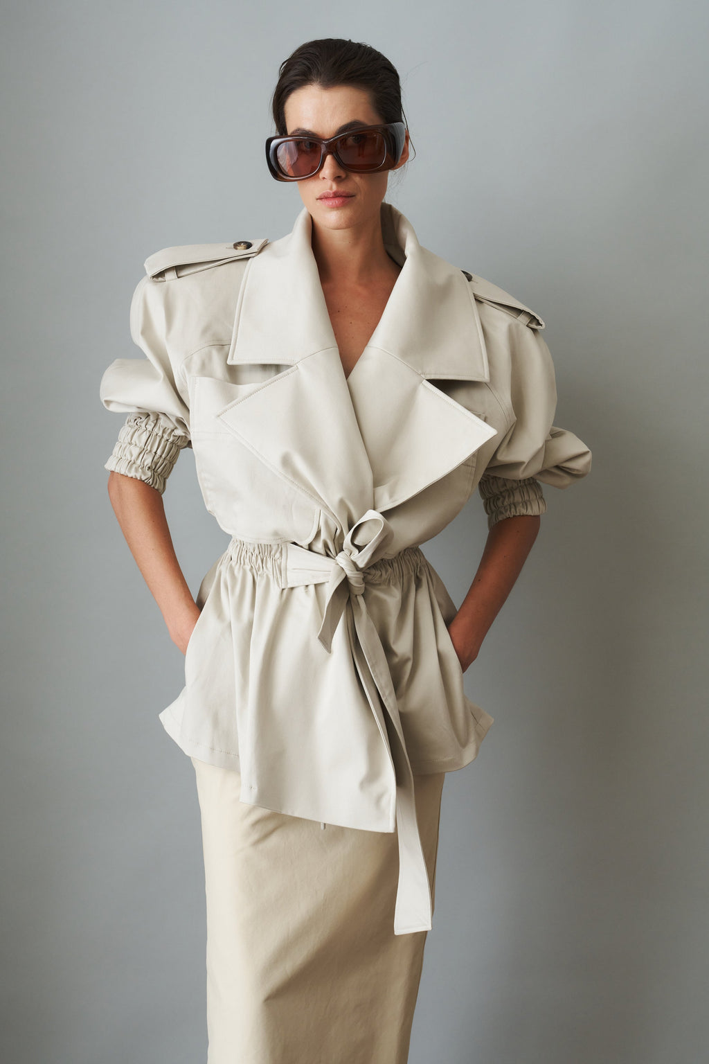 Women's cream trench coat with wide lapels, tie waist and elasticated cuffs