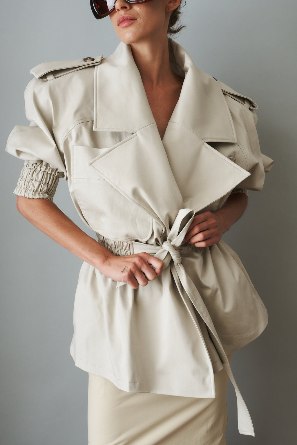 Women's cream trench coat with wide lapels, tie waist and elasticated cuffs
