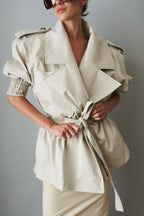 Women's cream trench coat with wide lapels, tie waist and elasticated cuffs