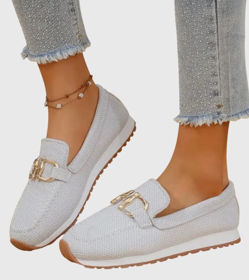 Women's textured slip-on loafers with decorative metal-tone buckles and ridged soles