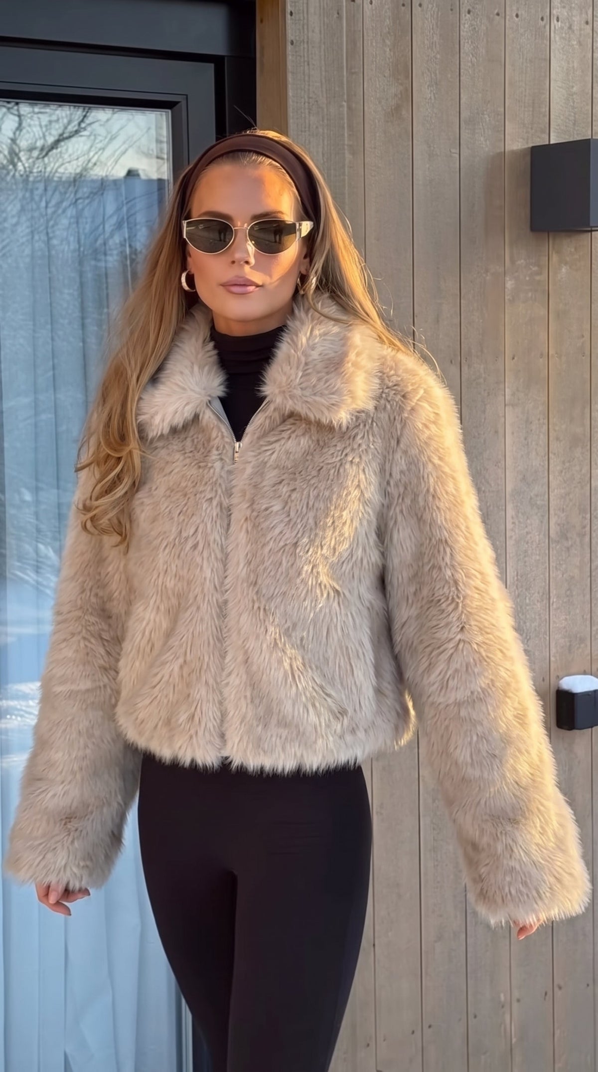 Woman wearing a beige faux fur bomber jacket with an oversized collar