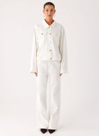 Women's oversized white denim jacket with shirt collar, chest pockets and snap fastenings
