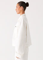 Women's oversized white denim jacket with shirt collar, chest pockets and snap fastenings