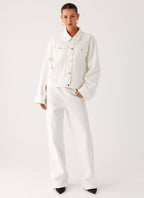 Women's oversized white denim jacket with shirt collar, chest pockets and snap fastenings
