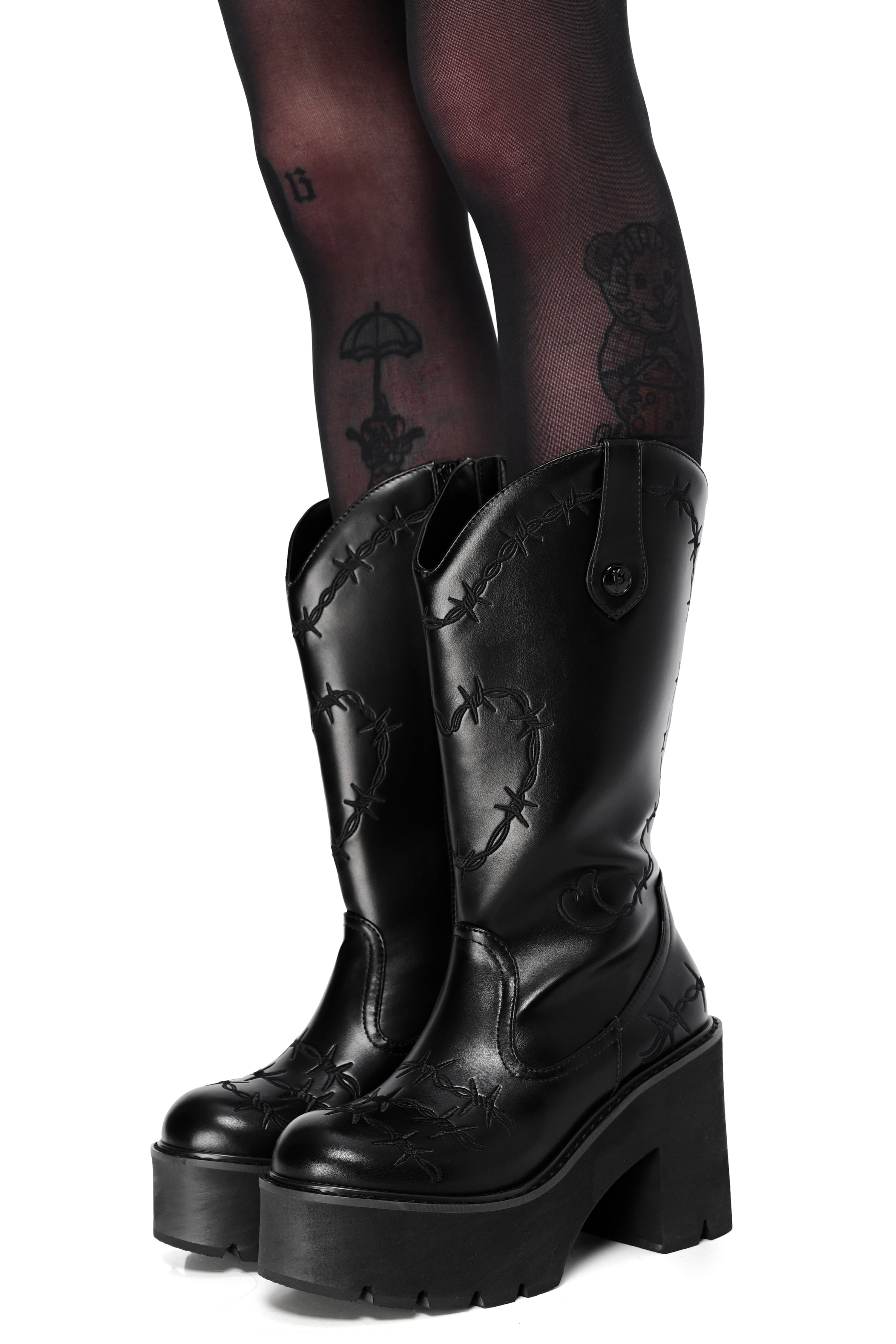 Black platform cowboy boots with barbed wire stitching and buckle straps