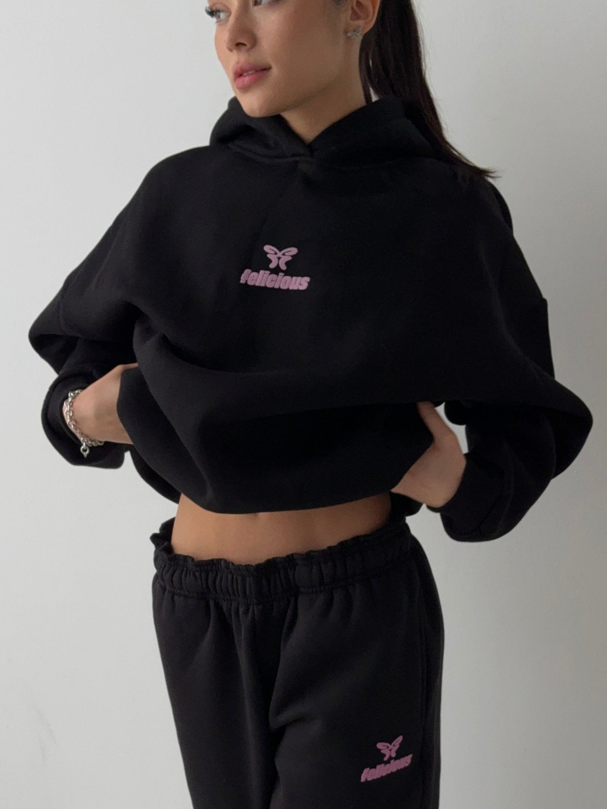 Women's black cropped hoodie with hood and pink chest logo