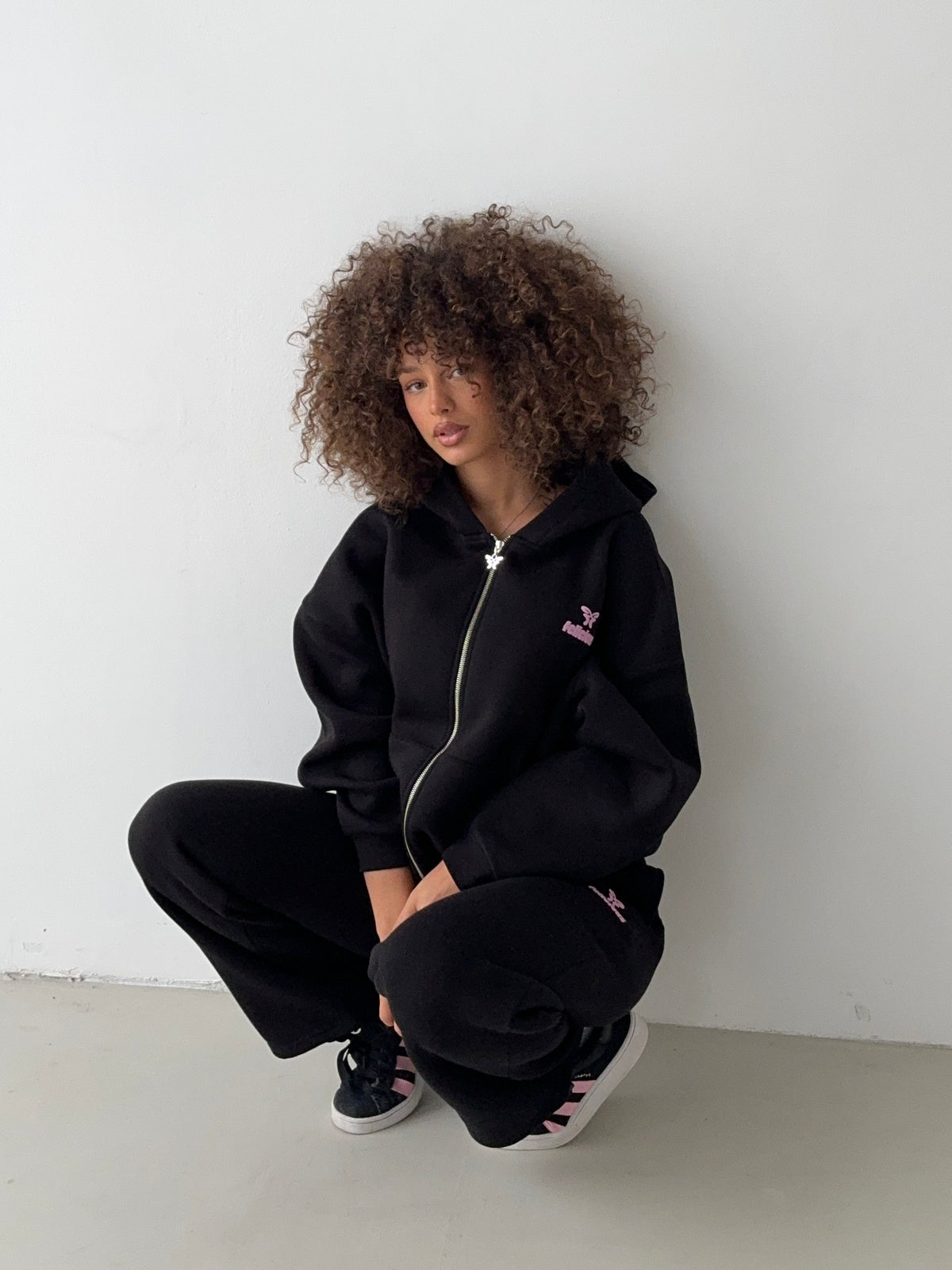 Women's black zip-up hoodie with hood, pink logo and front pocket