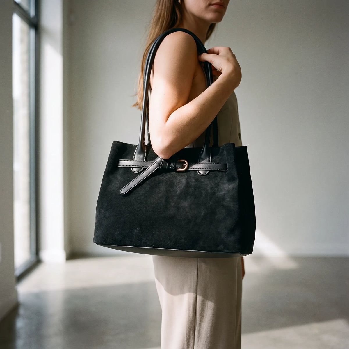 Structured women's tote bag with dual handles and front belt buckle detail