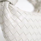 Woven handbag with braided knot handle and curved hobo shape