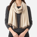 Women's cream knitted shawl scarf with contrasting border draped around the neck
