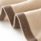 Women's cream knitted shawl scarf with contrasting border draped around the neck