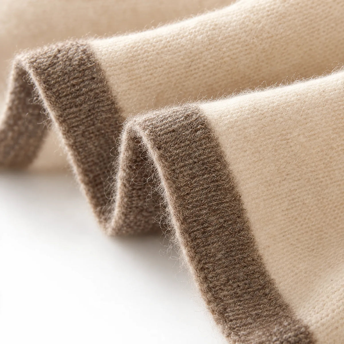 Women's cream knitted shawl scarf with contrasting border draped around the neck