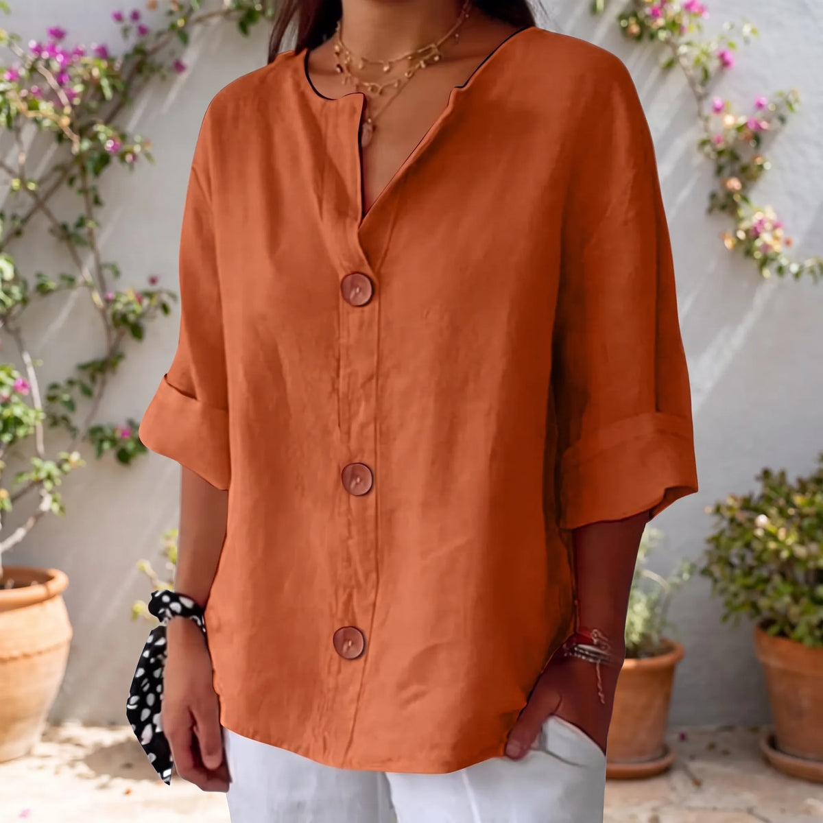 Women's orange V-neck button-down blouse with rolled three-quarter sleeves