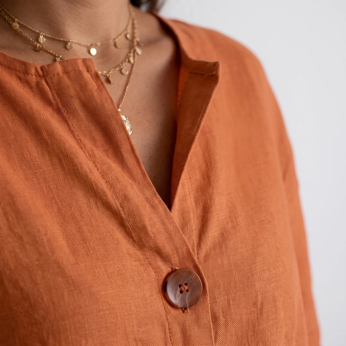 Women's orange V-neck button-down blouse with rolled three-quarter sleeves