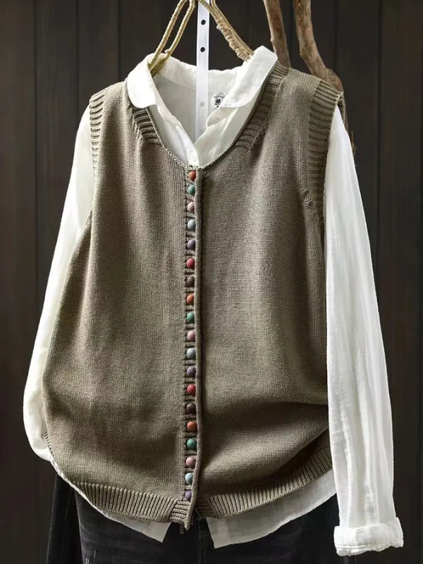 Women's sleeveless button-front cardigan vest with multicoloured buttons over a white blouse