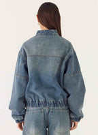 Women's blue denim bomber jacket with high collar and zip front