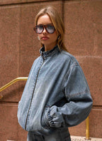 Women's blue denim bomber jacket with high collar and zip front