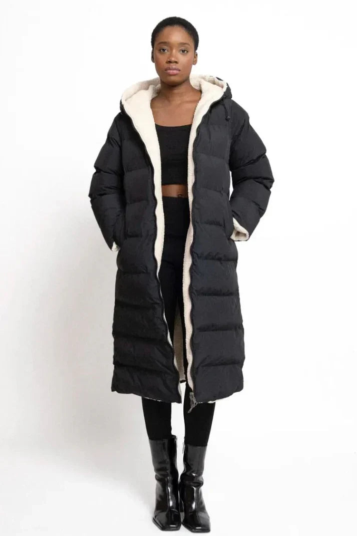 Woman wearing a reversible longline hooded padded coat with a quilted side and textured reverse