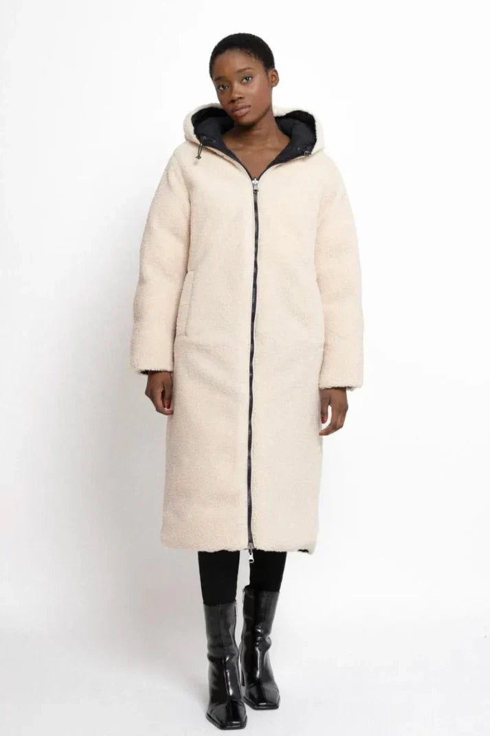 Woman wearing a reversible longline hooded padded coat with a quilted side and textured reverse