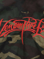 Green camouflage hooded jacket with tan fur-effect trim and red embroidery