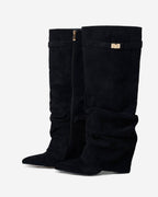 Women's black slouchy knee-high boots with pointed toes and buckle strap details
