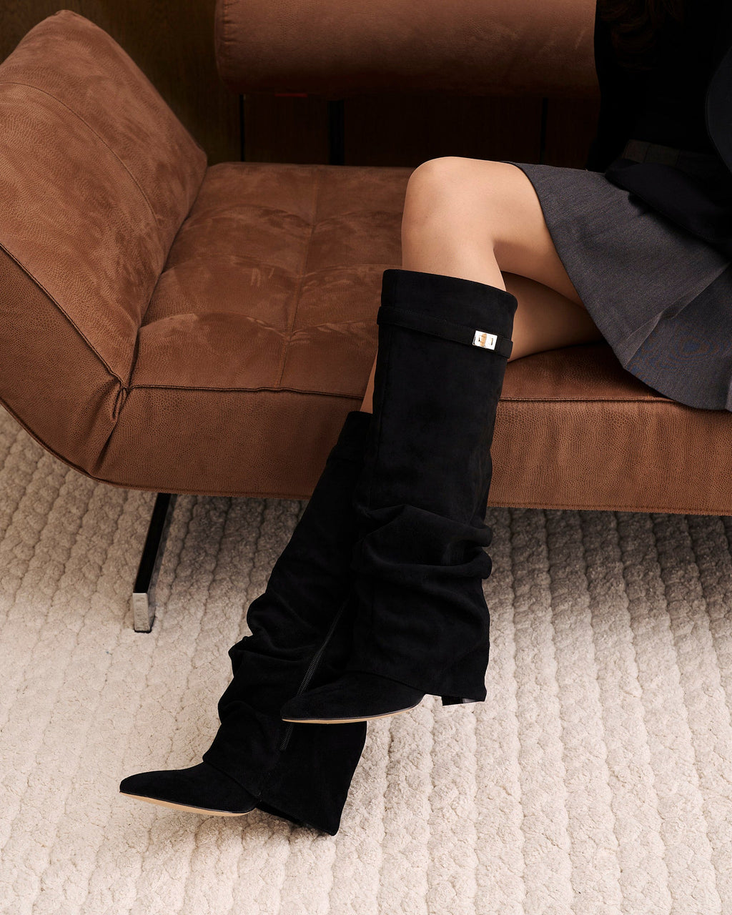 Women's black slouchy knee-high boots with pointed toes and buckle strap details