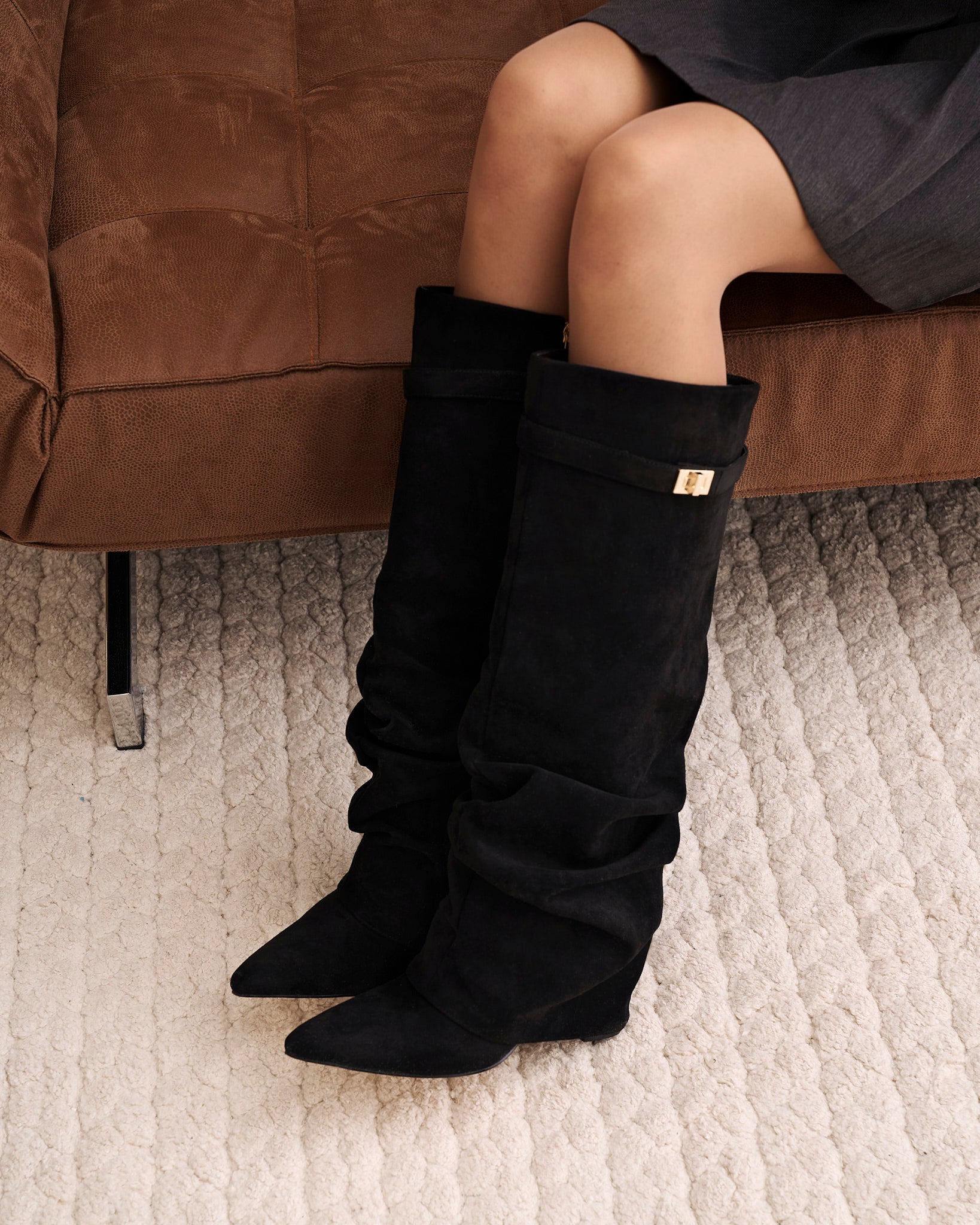 Women's black slouchy knee-high boots with pointed toes and buckle strap details
