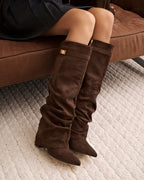 Women's brown slouchy knee-high boots with pointed toes, low heels and buckle straps