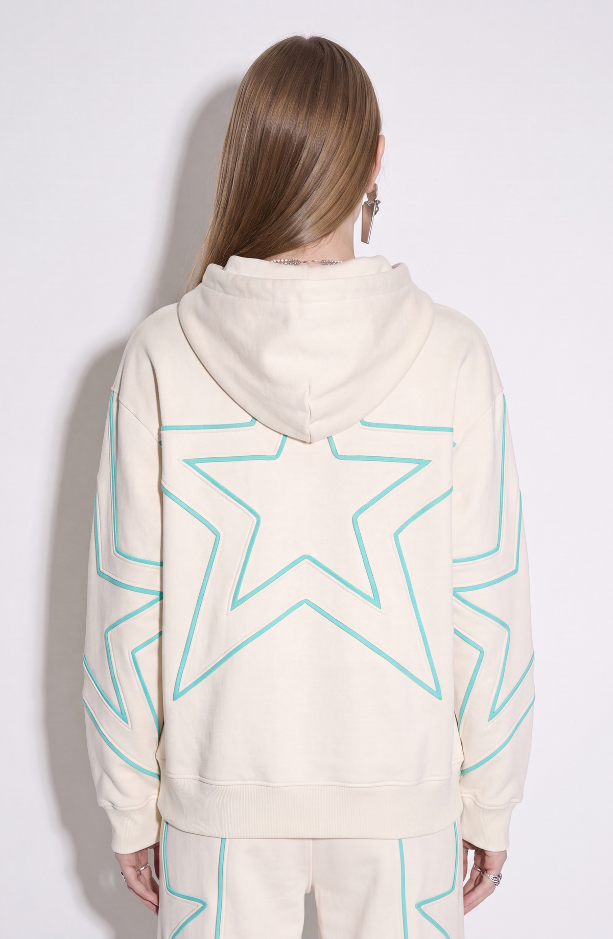 Cream hoodie with turquoise outlined star motifs, drawstring hood and front kangaroo pocket