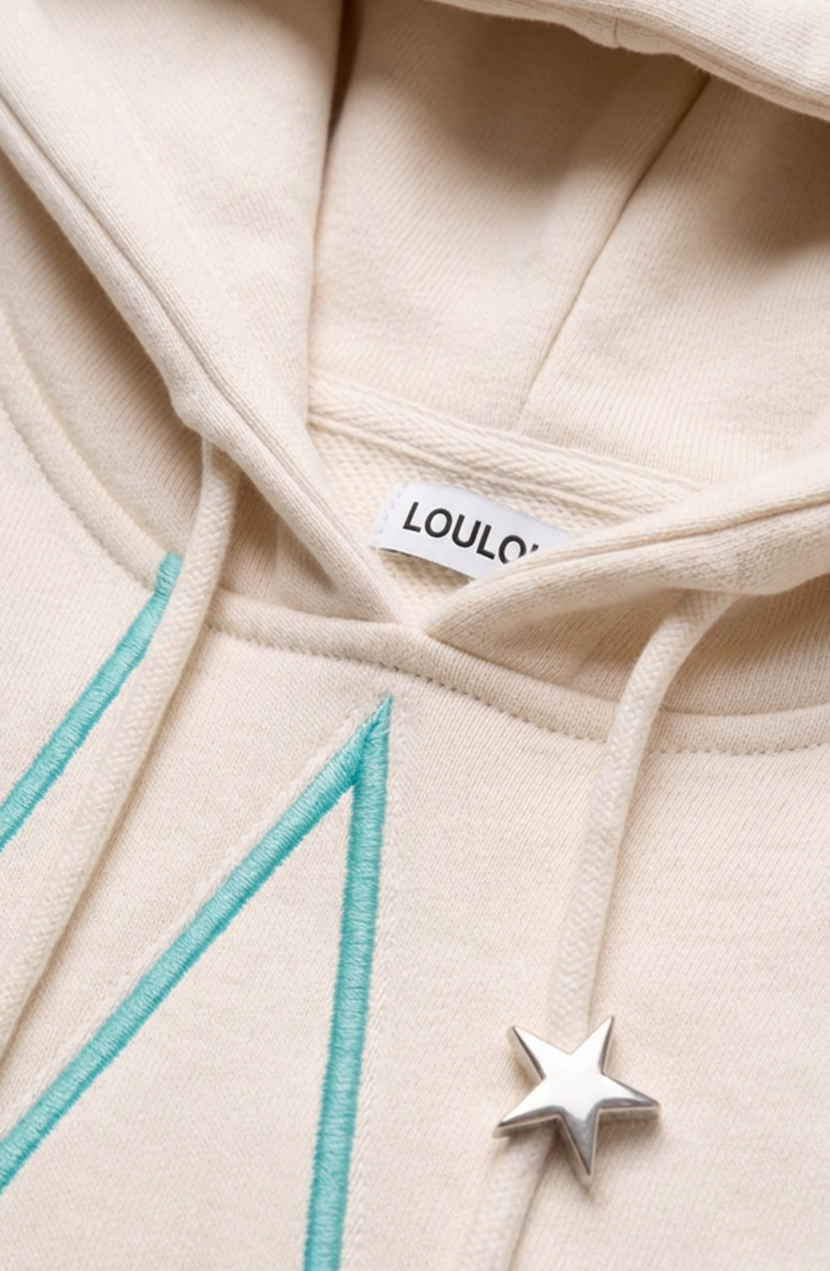 Cream hoodie with turquoise outlined star motifs, drawstring hood and front kangaroo pocket