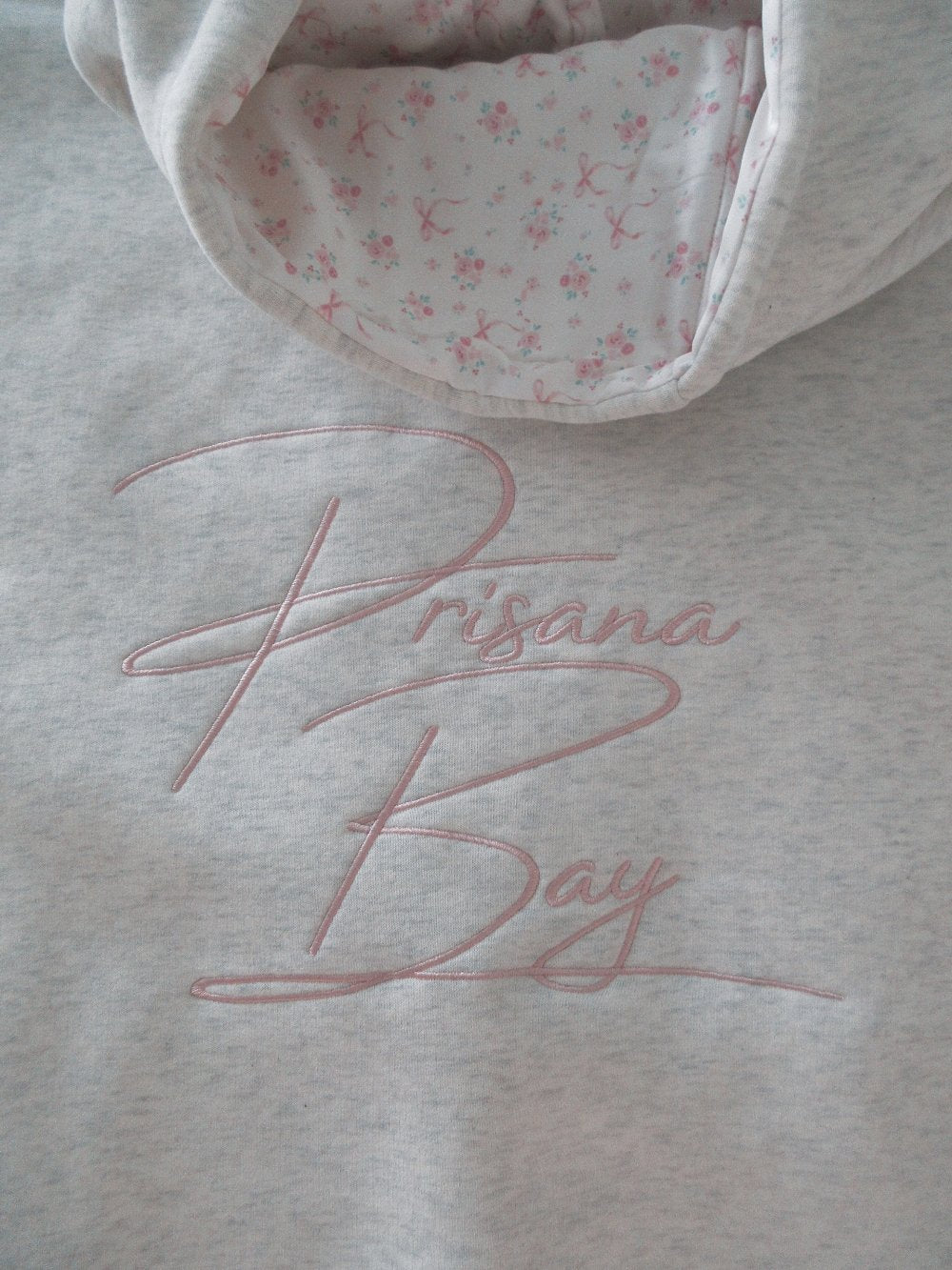 Women's light grey hooded sweatshirt with pink embroidery and floral-lined hood
