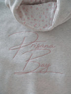 Women's light grey hooded sweatshirt with pink embroidery and floral-lined hood