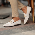 Men's slip-on loafers with decorative buckle and low heel shown in beige and black