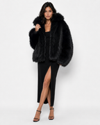 Woman wearing a black long-haired fur coat with a wide collar