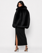 Woman wearing a black long-haired fur coat with a wide collar
